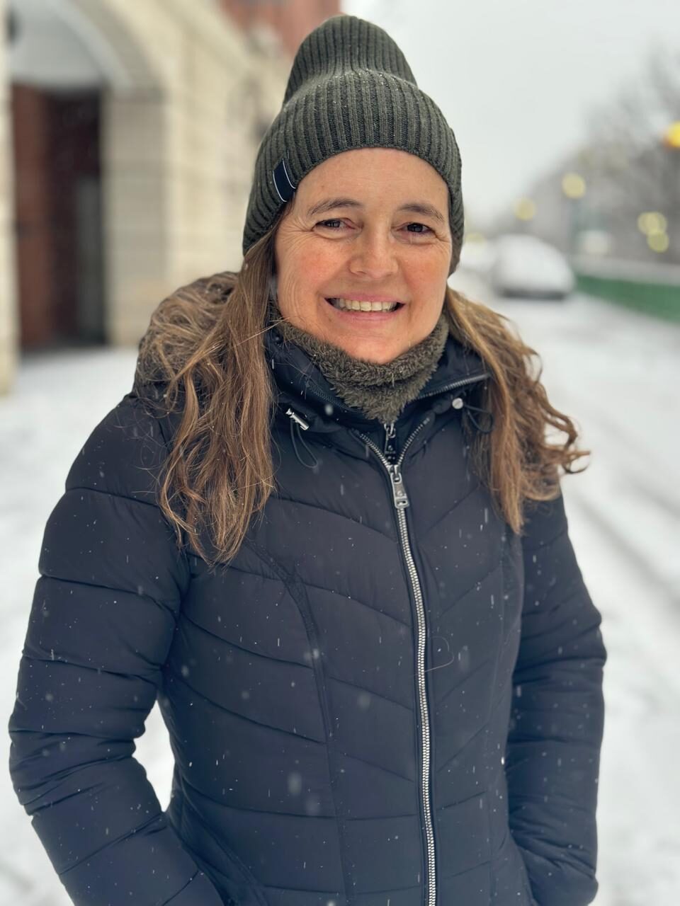 Georgina Elustondo smiling on a snowy street, wearing a wool hat and a dark coat
